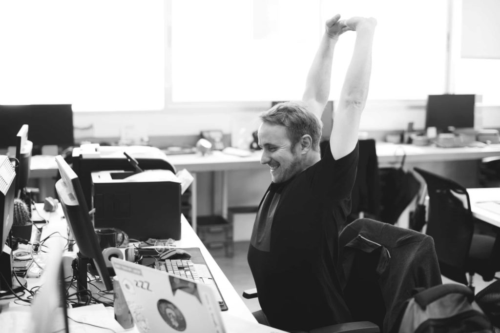 homem se espreguicando em frente ao computador