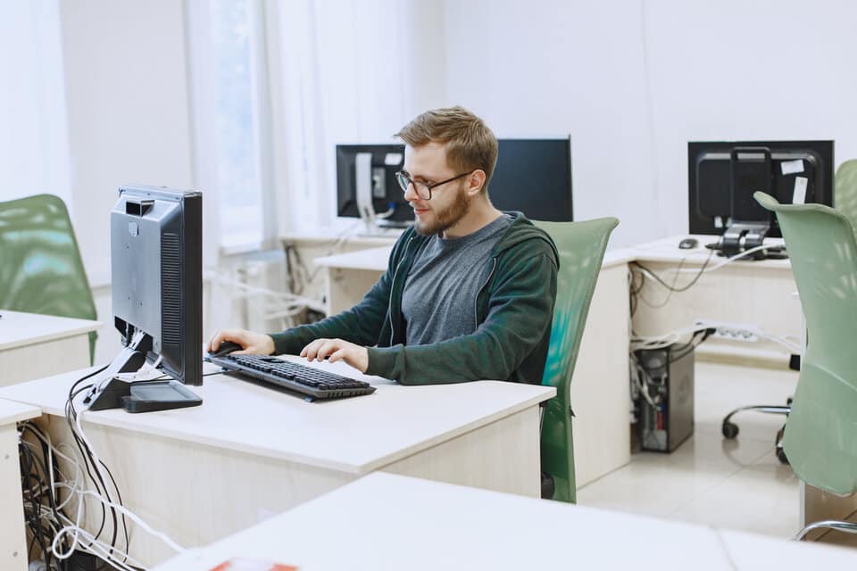 Homem sentado em frente ao computador pesquisando saláro de programador